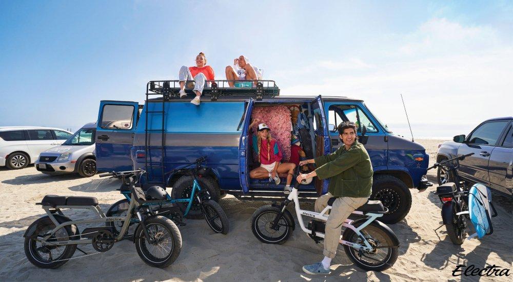 group of people sitting on a van with one person on an electric bike